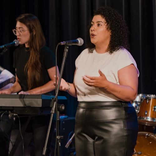 Dupla de alunas em apresentação, uma cantando e a outra no teclado