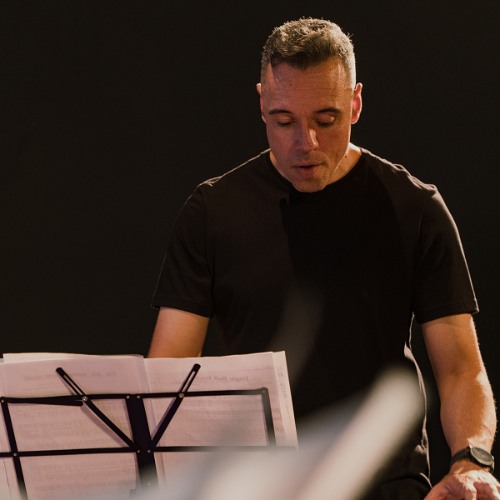 Professor lendo a partitura na estante durante o ensaio